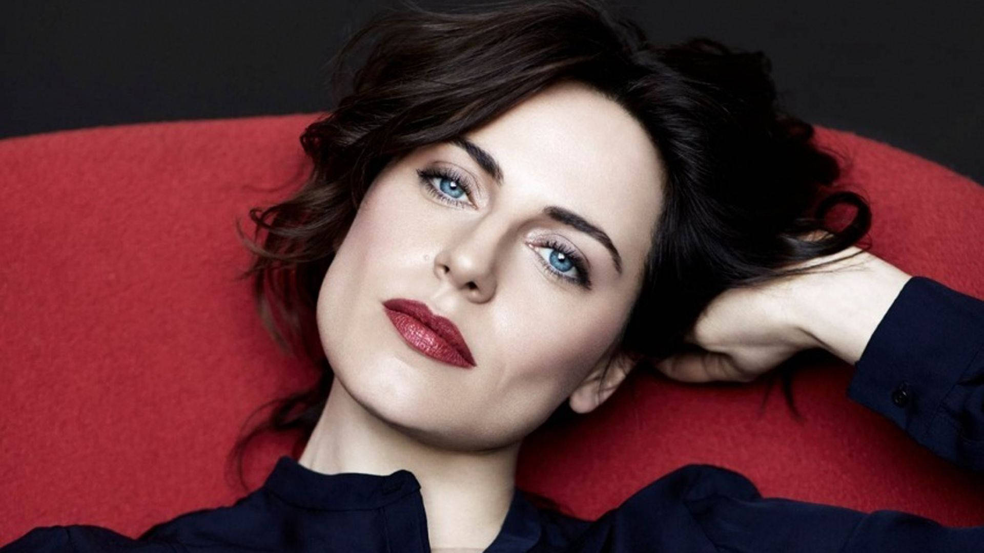 Caption: Antje Traue in Chic Red Chair Wallpaper
