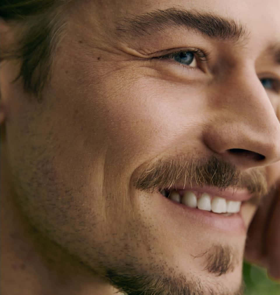 A Man With A Mustache And Blue Eyes Smiling