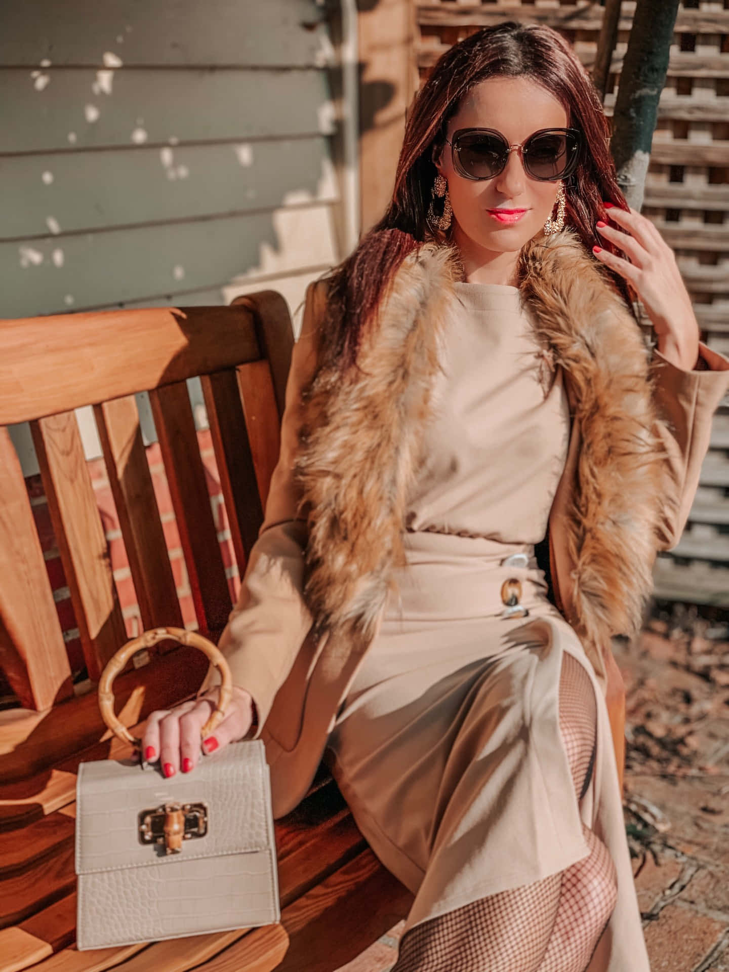 A Woman In A Fur Coat And A Beige Dress Sitting On A Bench