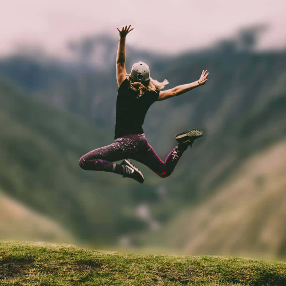 Blurry Background Woman Jumping On A Mountain
