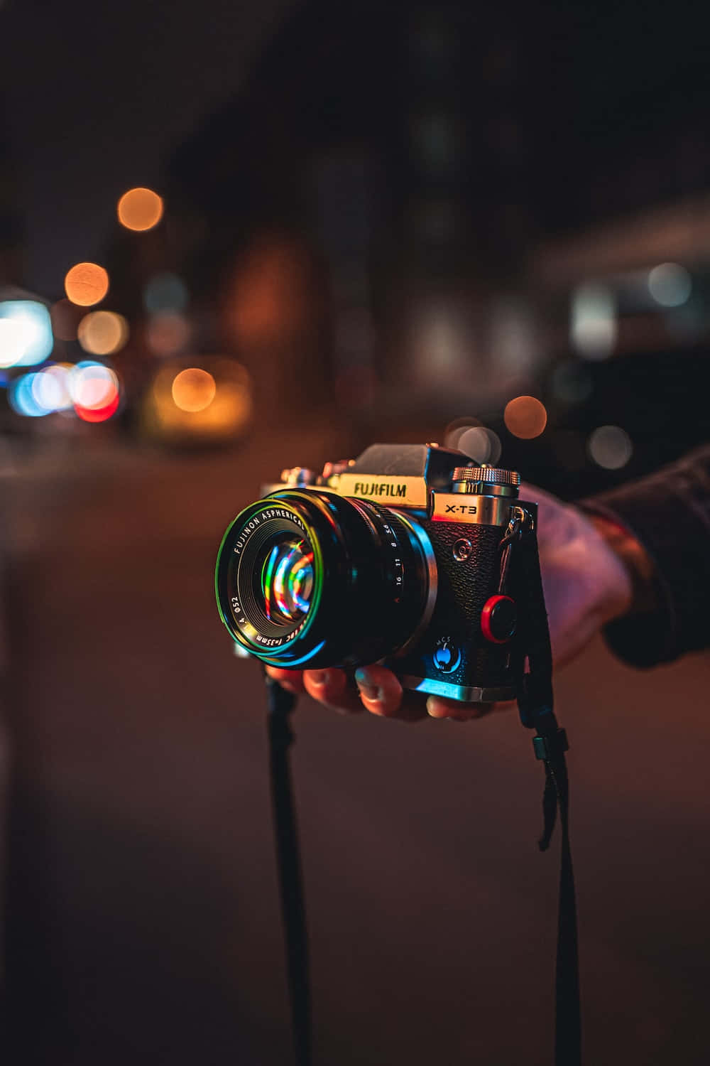 A Person Holding A Camera At Night