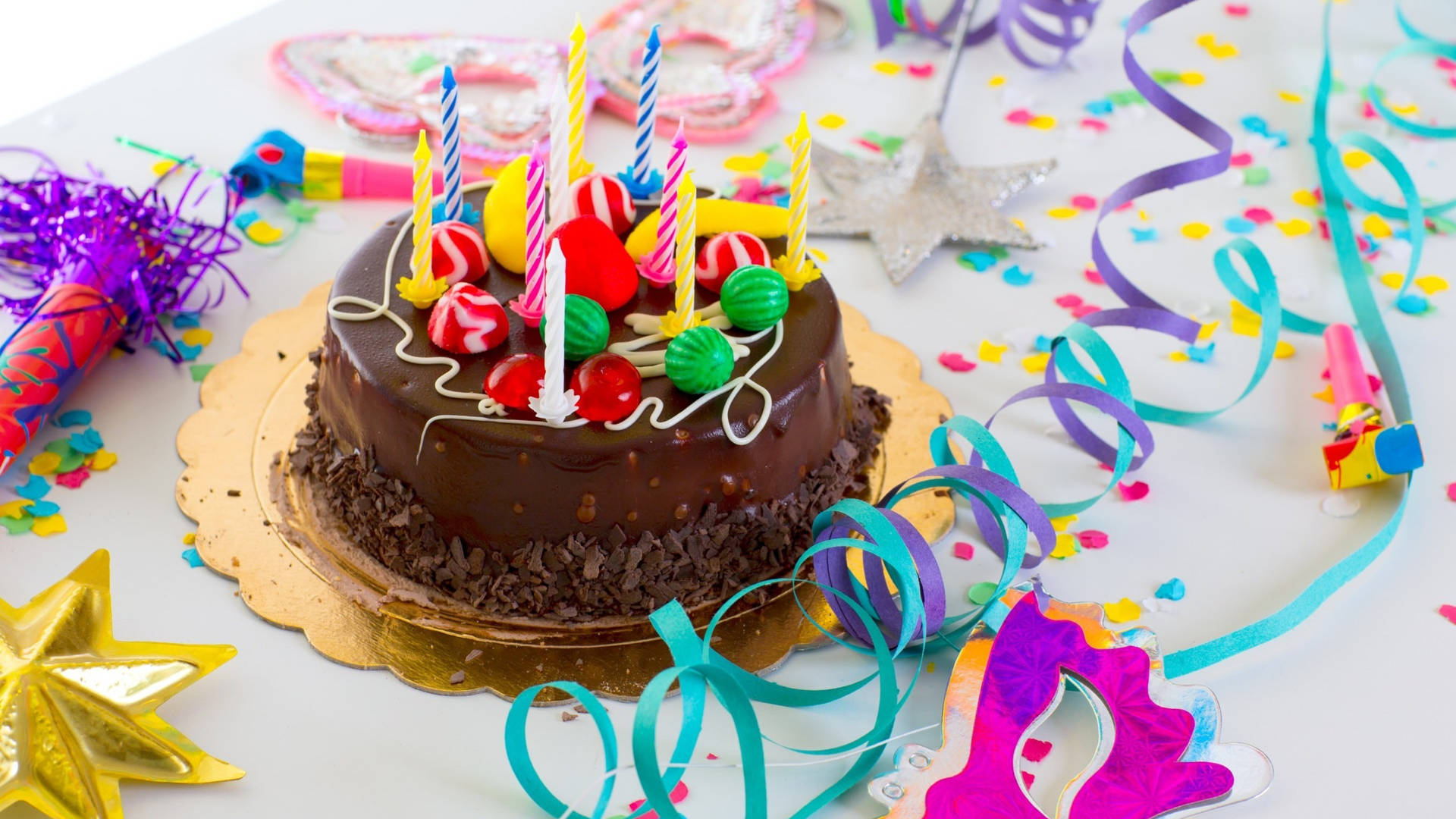 A vibrant and colorful birthday cake with lit candles Wallpaper