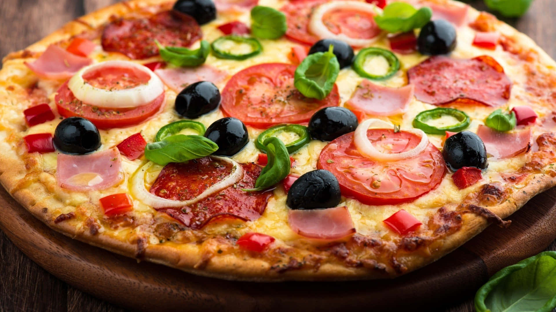 A Pizza With Olives, Tomatoes, And Olives On A Wooden Plate Wallpaper