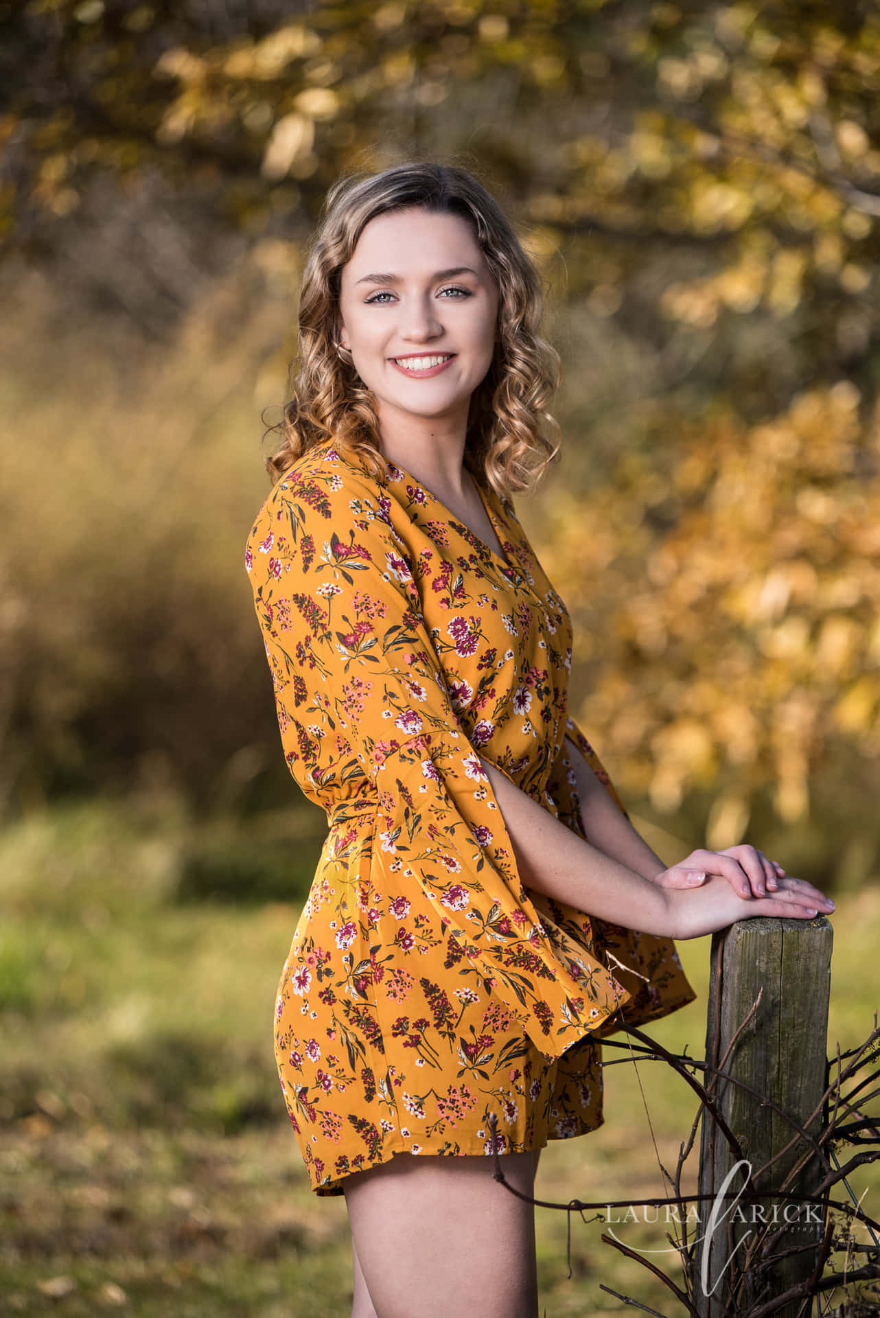 A Beautiful Young Woman In A Yellow Dress Leaning Against A Fence
