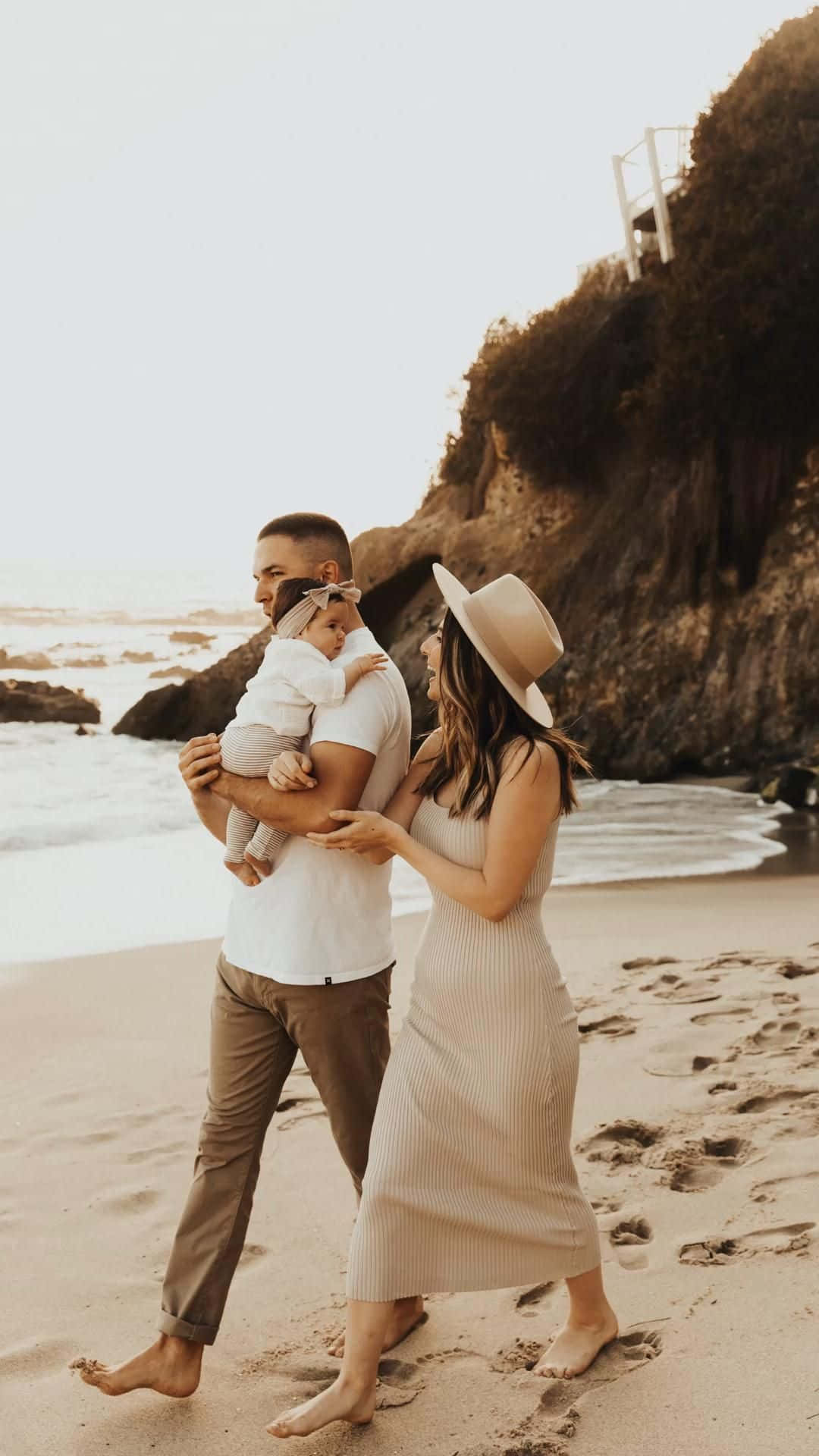 a family walking on the beach with their baby