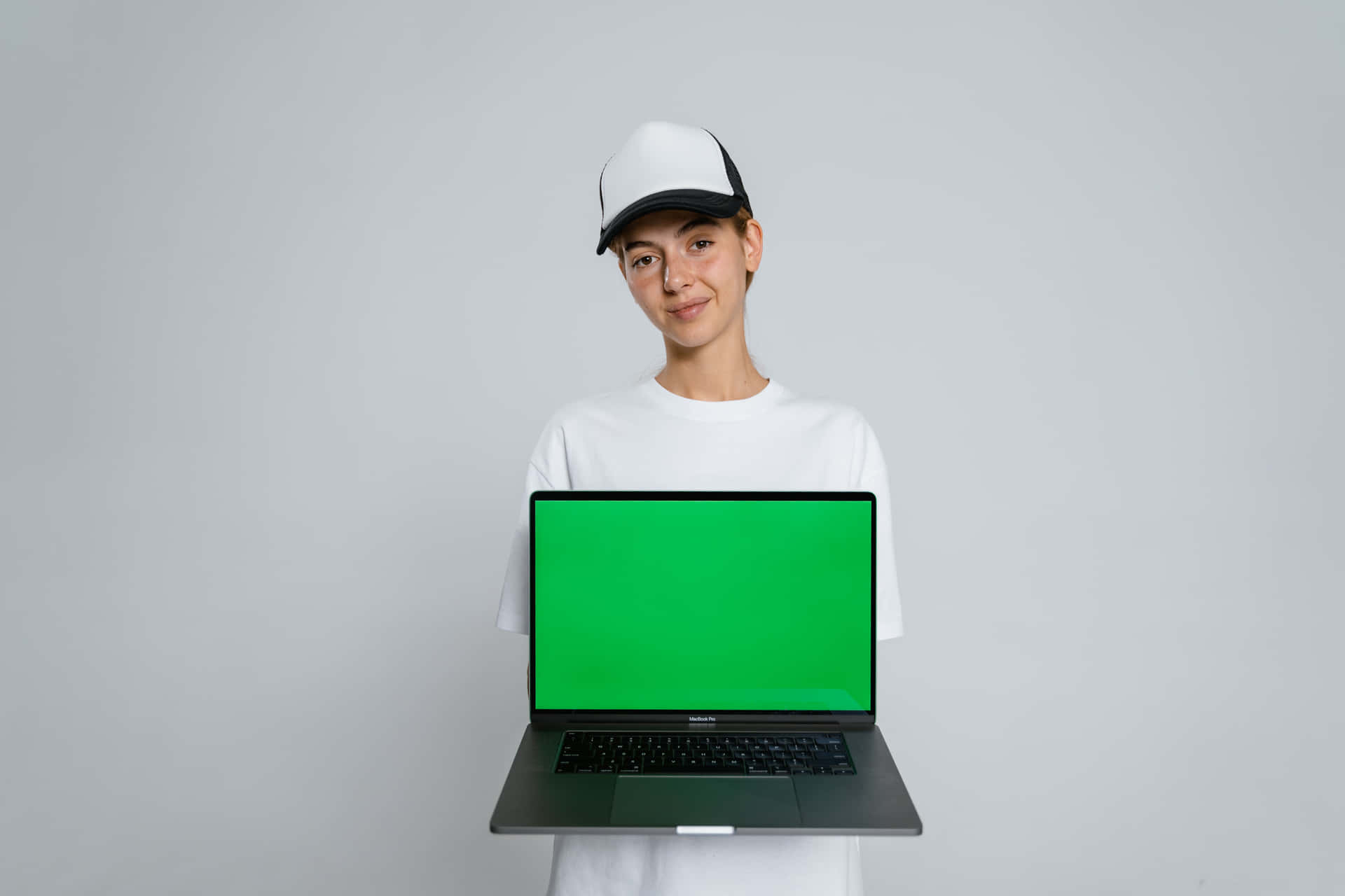 a young man holding a laptop with a green screen