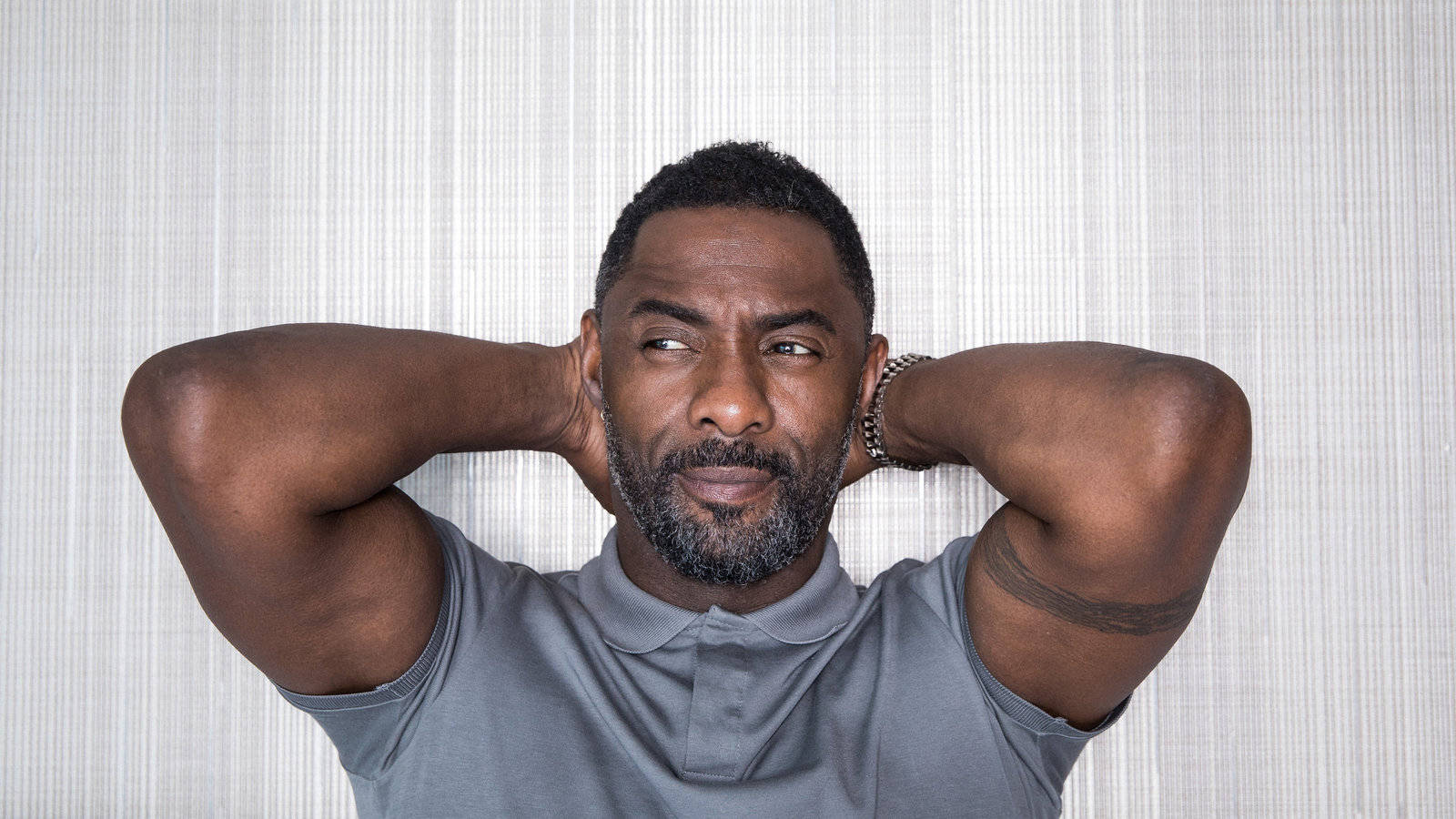 "Idris Elba lounging with hands on back of head" Wallpaper