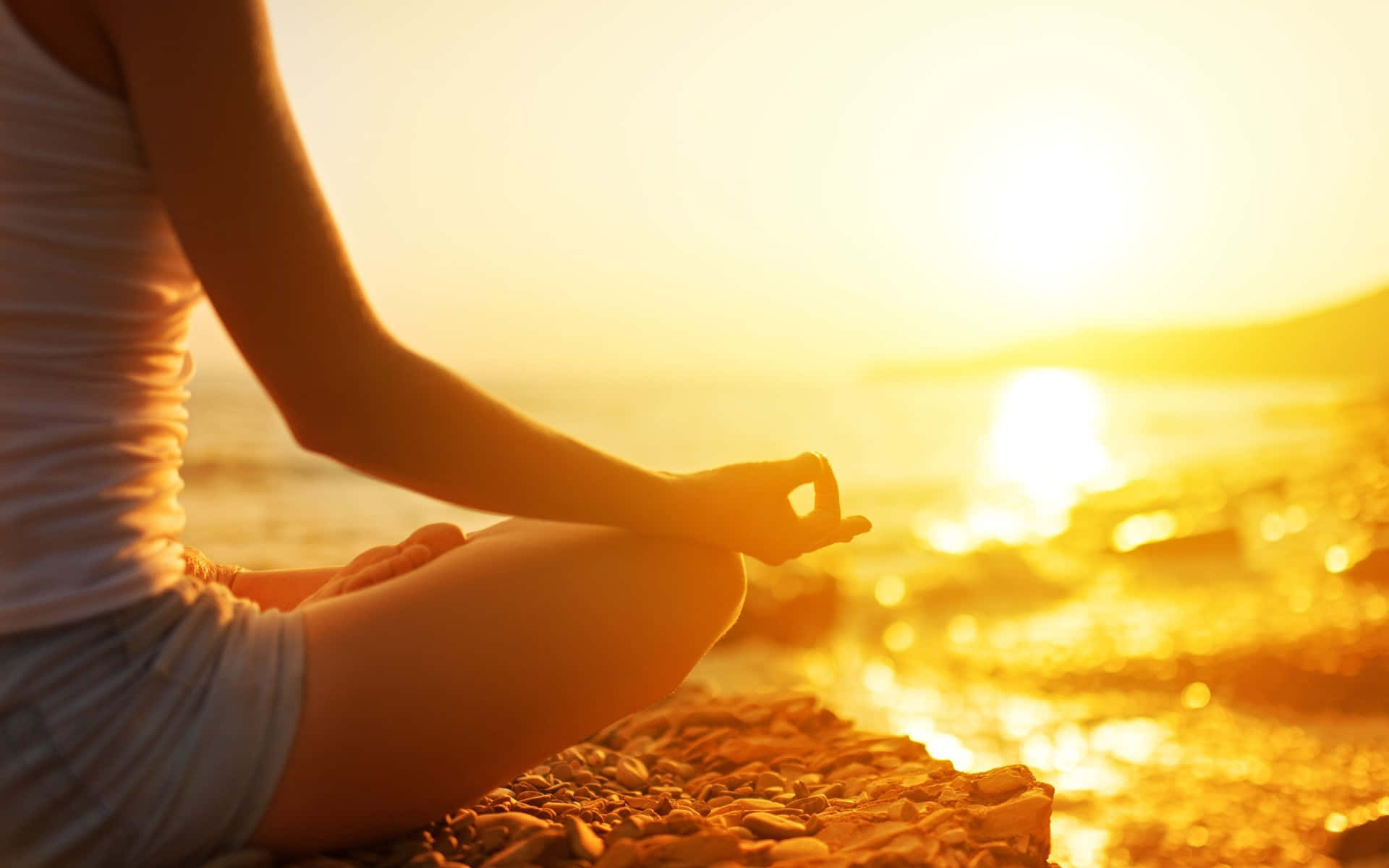 Woman Meditating On The Beach At Sunset