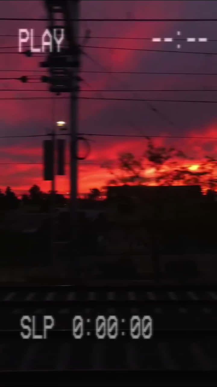 A Train Is Traveling Through A Red Sunset Wallpaper