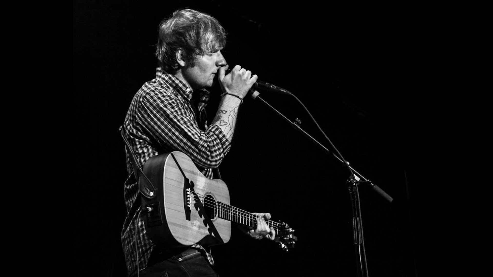 Ed Sheeran strumming away in front of a Live Audience Wallpaper