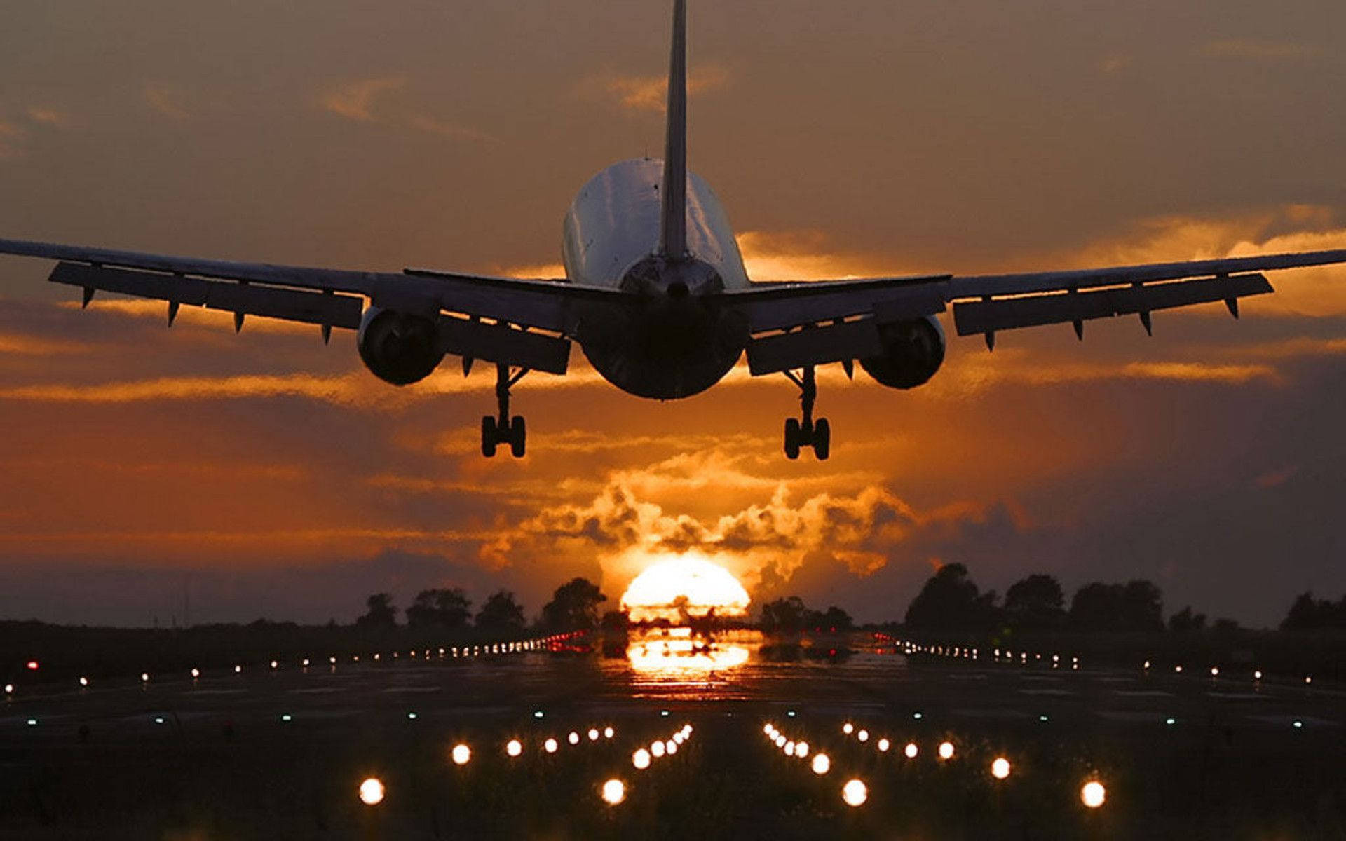An incredible sunset view of an airplane making a final descent. Wallpaper